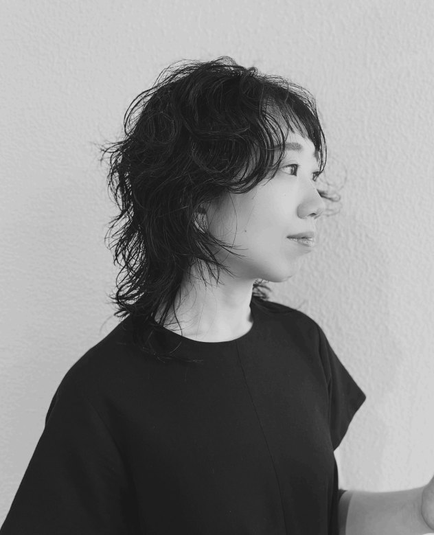 田村真夏。白い壁を背に横を向いている、白黒の写真